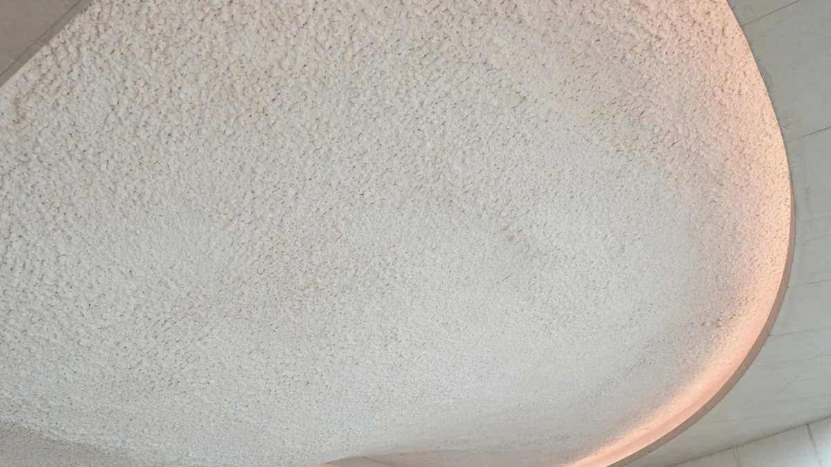 Flocage acoustique projeté sur un plafond béton courbe